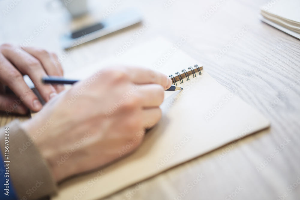Poster a man's hand is caught in close-up, busily writing in a notepad, while the background is out of focu