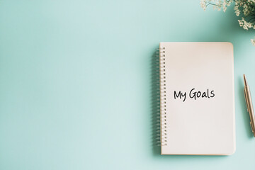 The notepad says &ldquo;my goals&rdquo; on a blue background. Concept: the beginning of a new year with new goals and plans. Notepad with pen.