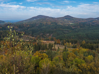 Panoramic view from viewpoint Stredni vrch near Dolni Prysk, Ceska Kamenice. Autumn landscape with colorful forest, hills and blue cloudy sky in Luzicke hory Lusatian Mountains, Czech Republic.