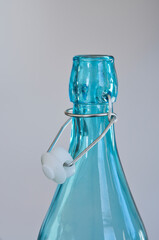 Close-up shot of empty blue bottle neck isolated on light background.