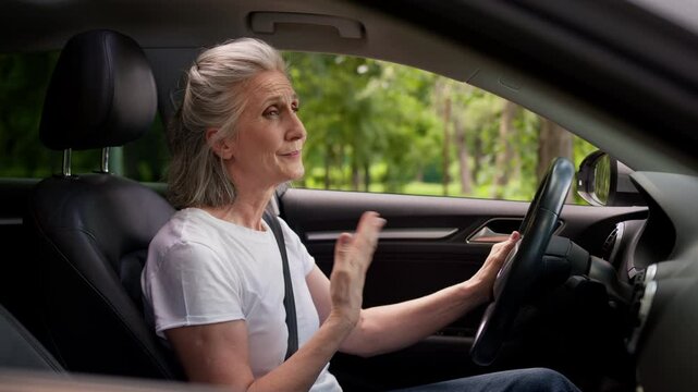 Caucasian mature elderly woman senior lady female automobile taxi driver pensioner inside auto vehicle waving hand suffering heat opening windows broken air conditioner problem hot weather overheating