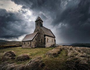 Fototapeta premium A solitary medieval stone church stands dramatically on a hilltop against dark, stormy clouds in a moody landscape.