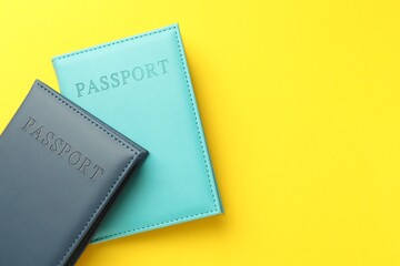 Passports in color covers on yellow background, top view. Space for text