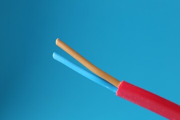 Red stripped electrical wire on light blue background, closeup