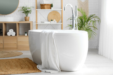 Bathtub with towel, shelving unit in interior of bathroom