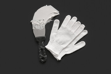 Knife with putty and gloves on black background