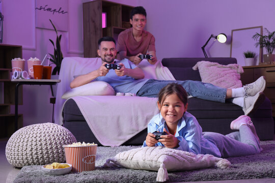Little girl with her family playing video game at home in evening