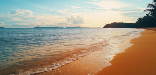 Golden sunset paints the sky above the tranquil ocean waves, casting a warm glow on the sandy shore