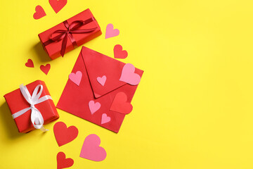 Envelope with paper hearts and gift boxes on yellow background. Valentine's day celebration