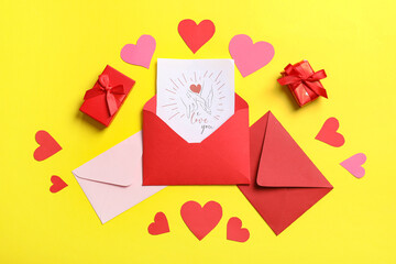 Envelopes with gift card, boxes and paper hearts on yellow background. Valentine's day celebration
