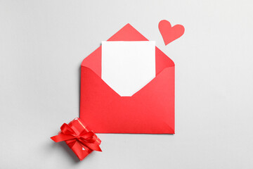Envelope with blank card, paper heart and gift box on grey background. Valentine's day celebration