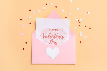 Envelope with gift card and confetti on beige background. Valentine's day celebration