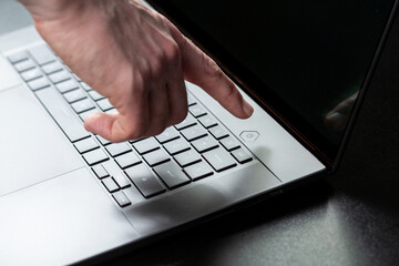 Closeup of a male hand going to press  laptop power button