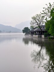 Obraz premium Serene Lake Landscape with Mist and Reflection of Traditional Architecture