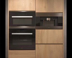 Fototapeta premium Modern kitchen appliances in a sleek wood panel setting, featuring a black coffee machine and two ovens.