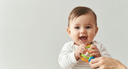 Happy caucasian baby playing with colorful rattle in bright setting
