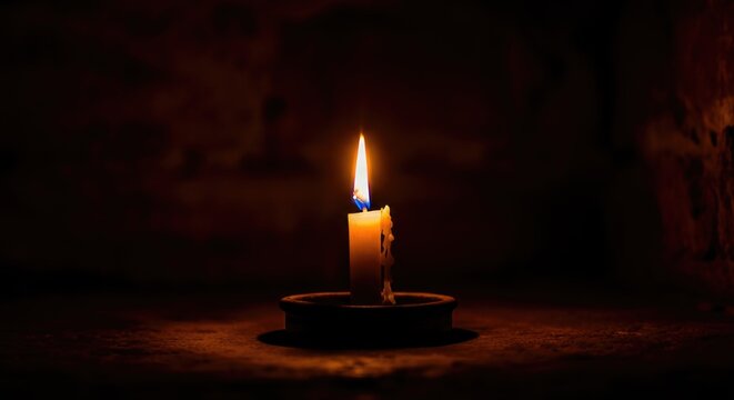 Single candle illuminating dark room with warm glow