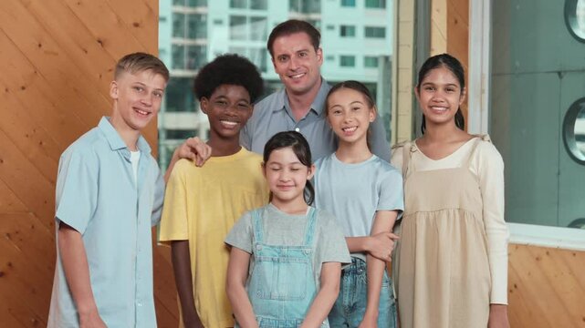 Happy teacher and diverse student standing while smilling to camera. Professional smart instructor with high school children with mixed races in casual outfit pose at camera with cheerful. Edification