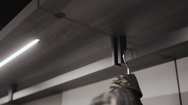 A stylish minimalist interior featuring hanging clothing items and contemporary modern lighting