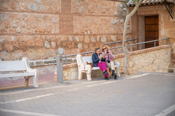 Obraz premium Two women sitting on a bench, reading a map during a city tour in Spain