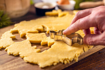 Male hands preparing festive Christmas cookies on wooden table