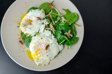 Salad Lyonnaise - Warm bacon & egg salad with spinach and pickled onions, on a black background, breakfast recipe idea