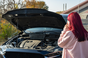 The female driver's car broke down, the hood of the car was open, the woman called the insurance office