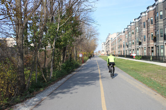 Man riding a bicycle on the Monon Greenway Path near apartment buildings in Carmel, Indiana