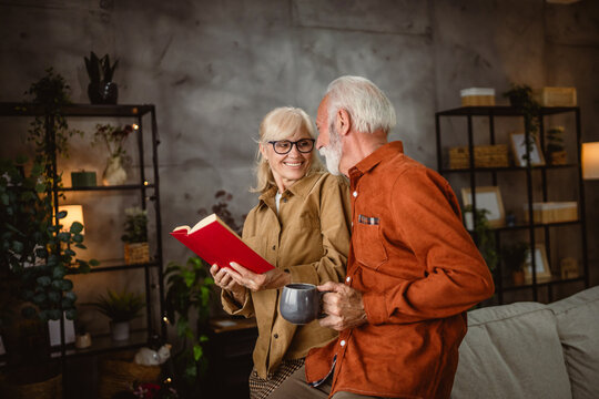 senior couple husband and wife stand and read a book together