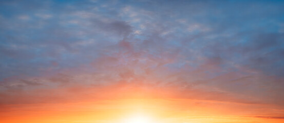 A beautiful blue sky with a sun in the middle. The sun is setting and the sky is orange