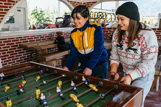 Friends playing foosball table game during christmas holidays