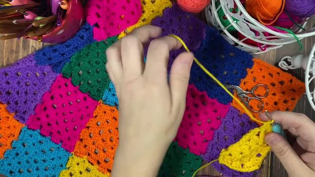 Crocheting granny square blanket plaid process and woman's hands hobby handmade handiwork clews and hook cozy winter autumn fall video