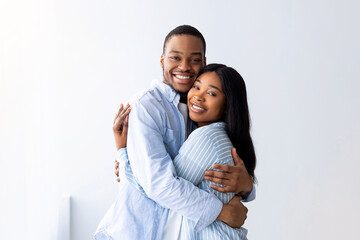 Loving african american couple standing in their house, hugging and smiling, being happy of buying own lodging. Cheerful young family relocating to new property, free space