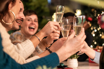 Friends toasting champagne at Christmas party, joyful celebration with holiday lights