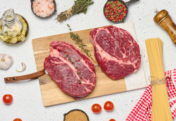 Raw beef steak chuck eye roll on wooden board. Spices for cooking Himalayan salt, peppercorns and thyme sprigs