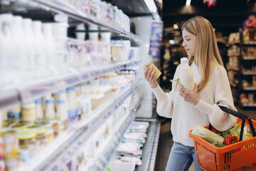 Customer choosing products in supermarket dairy section