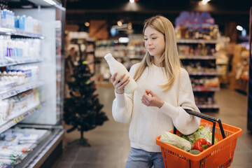 Customer choosing milk bottle in supermarket dairy section