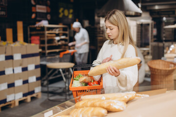 Woman choosing fresh bread in supermarket bakery department