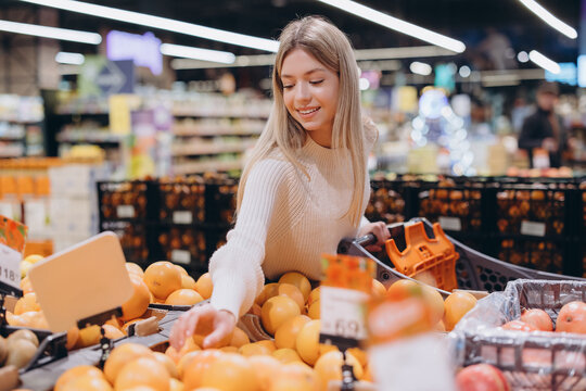 Woman choosing oranges in supermarket fruit and vegetable section