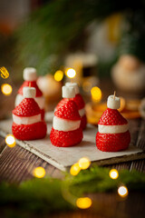 Strawberry and marshmallow in the shape of santa, festive food on table with christmas lights