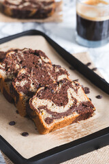Close-up of freshly sliced chocolate marble bread made from whole wheat and spelt flour and a glass of espresso at background. A nutritious yet indulgent treat.