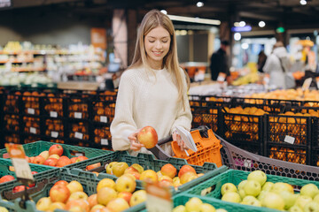 Young woman choosing apples in supermarket