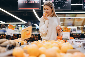 Woman smelling orange at grocery store fruit stand
