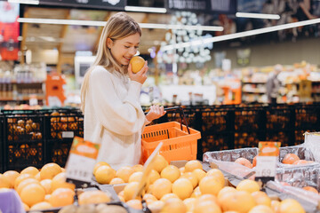 Woman smelling orange at the supermarket choosing fruits