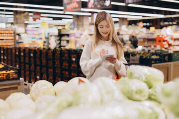 Woman taking notes on shopping list in supermarket