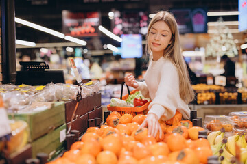 Customer choosing persimmon fruit at grocery store