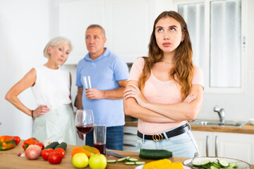 Offended young woman standing back to her parents, not speaking at home