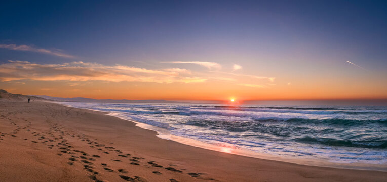 Monterey Bay Sunset with lonely beachcomber footprints.  Beach stretches forever