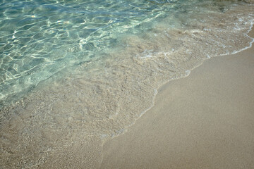 Small water wave in quiet transparent turquoise Mediterranean waters sandy beach in Puglia, Italy