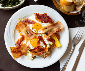 Delicious breakfast - scrambled eggs with bacon and french fries